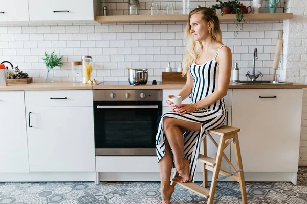 Fotó a konyhában hosszú csíkos ruha gyönyörű nő — Stock Fotó