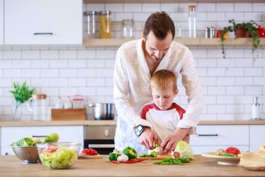 Genç baba ve oğul sebze ile masada yemek görüntü