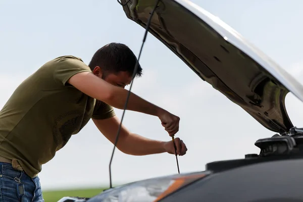 Photo of young man mending broken car with open hood