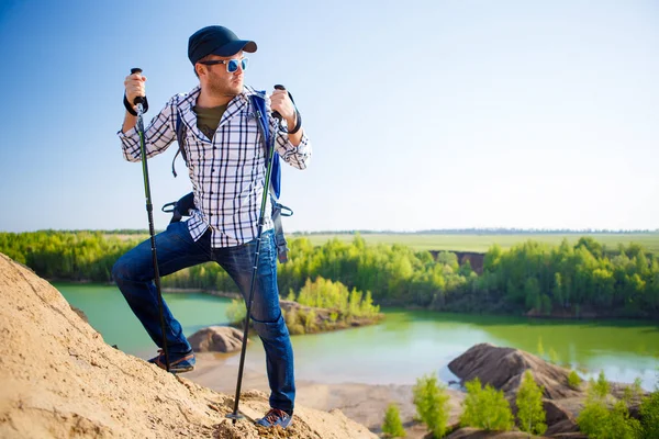 Picture of tourist man with backpack with sticks for walking on hill — Stock Photo, Image