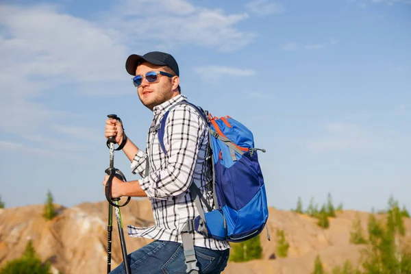 Foto eines Touristenmannes mit Mütze und Wanderstöcken auf einem Berg — Stockfoto