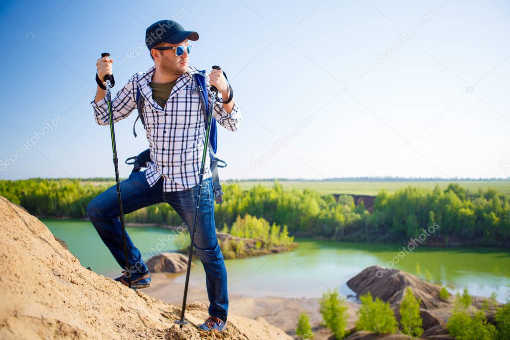 Picture of tourist man with backpack with sticks for walking on hill