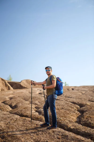 Foto eines jungen Touristenmannes mit Stöcken zum Wandern auf einem Hügel — Stockfoto