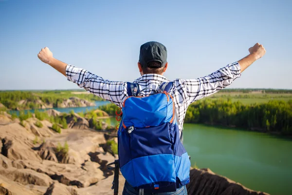 Picture from back of young tourist with backpack with hands up against background of mountain landscape, lake — Stock Photo, Image