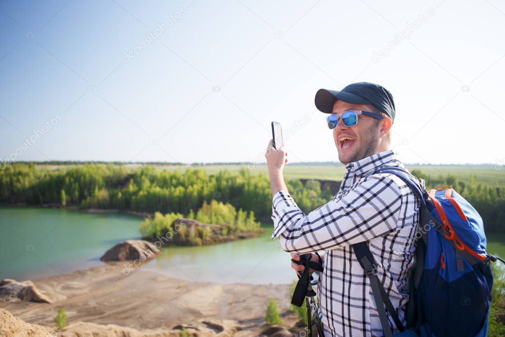 Photo of tourist man with walking sticks doing selfie on hill