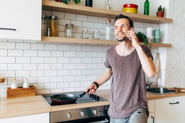 Kızartma tavası mutfakta telefonda konuşurken onun elinde olan brunet adam portresi