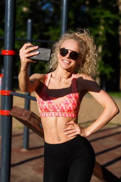 Foto van lachende sport vrouw dragen van een zonnebril doet selfie in park — Stockfoto