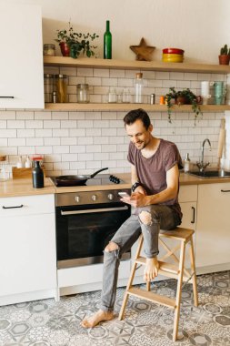 Kızartma tavası mutfakta telefonda konuşurken onun elinde olan brunet adam portresi