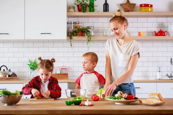 Genç Anne ile kızı ve oğlu kesme sebze masada görüntü