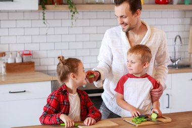 Görüntü bir genç baba ile kızı ve oğlu masada yemek