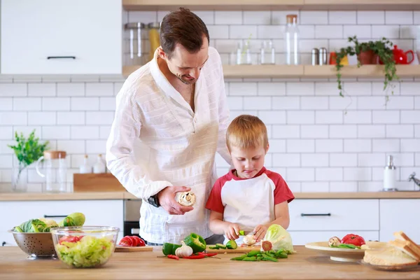 Fotografie mladých otce a syna vaření u stolu se zeleninou — Stock fotografie