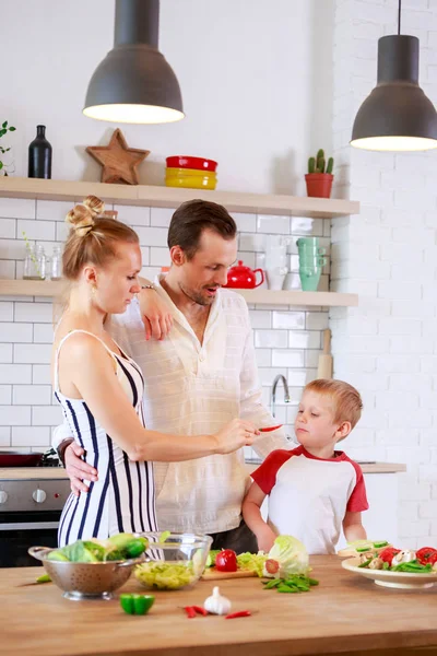 Anne, baba ve küçük oğul mutfakta yiyecek hazırlama resmi