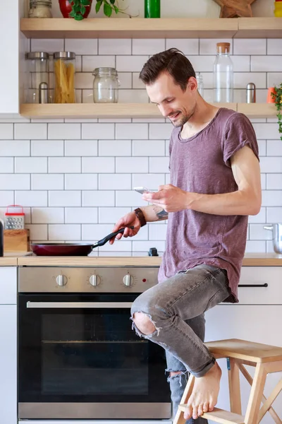 Kızartma tavası ve mutfakta elinde telefon brunet adamla fotoğrafı