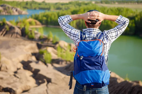 Beeld uit achterkant van jonge toeristische met rugzak met handen achter hoofd tegen de achtergrond van berglandschap, lake — Stockfoto