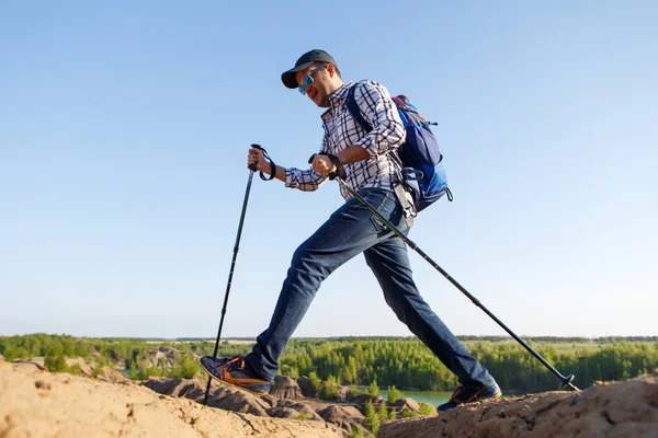 Photo of young tourist man with walking sticks walking in mountainous area — Stock Photo, Image