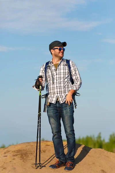 Photo of tourist man in sunglasses with sticks for walking on hill — Stock Photo, Image