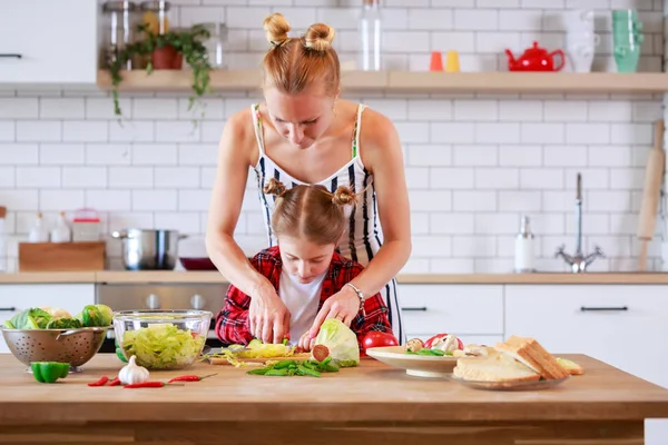 Foto mladé matky s dcerou vaření v kuchyni — Stock fotografie