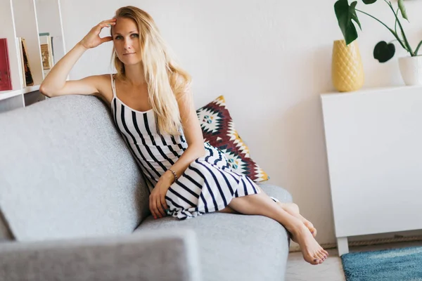 Образ молодої жінки, що сидить на сірому дивані — стокове фото