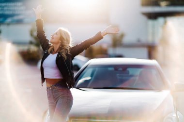 Araba arka plan üzerinde yükseltilmiş kollarıyla sarışın görüntüsünü