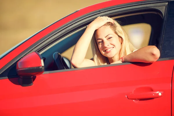 Imagem de loira feliz sentada em carro vermelho com janela aberta — Fotografia de Stock