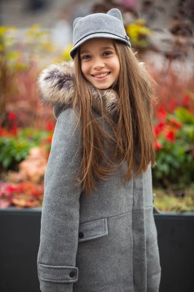 Foto eines lächelnden Mädchens mit grauem Hut und Mantel — Stockfoto