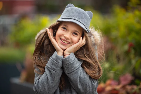 Foto eines lächelnden Mädchens mit grauem Hut und Mantel — Stockfoto