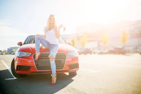 Foto di giovane donna con le chiavi in piedi vicino auto rossa su — Foto Stock