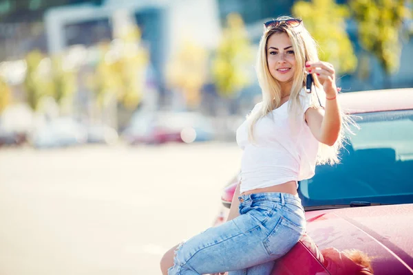 Image of blonde woman with keys standing near red car on summer day. — Stock Photo, Image