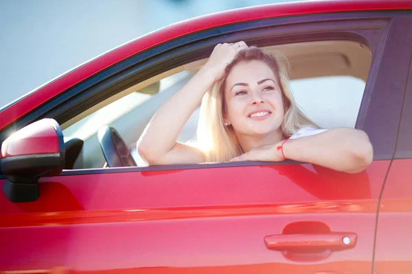 Foto de la hermosa rubia sentada en coche rojo con ventana abierta —  Fotos de Stock