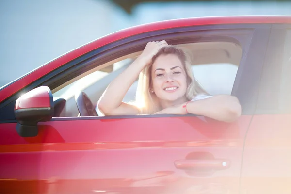 Imagen de la hermosa rubia sentada en coche rojo con ventana abierta —  Fotos de Stock