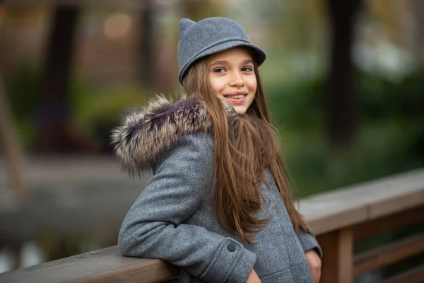 Foto von Mädchen mit grauem Hut und Mantel auf Holzbrücke in der Stadt — Stockfoto