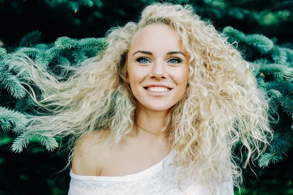 Foto de una mujer rizada de pelo largo junto a las ramas de abeto — Foto de Stock