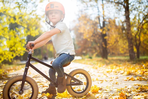 Photo of boy in helmet on running bike in autumn park — Stock Photo, Image