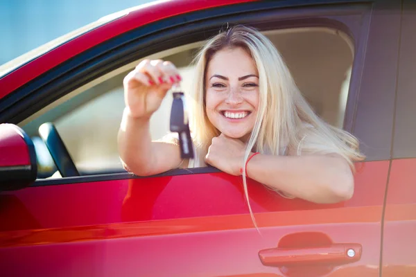 Foto de mulher loira bonita com chaves sentadas em carro vermelho com janela aberta — Fotografia de Stock