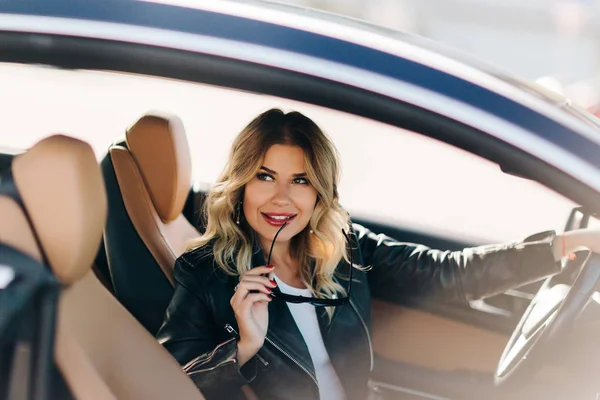 Foto de loira sorridente em mãos sentadas no carro enquanto dirige — Fotografia de Stock