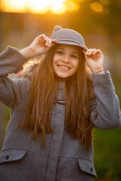 灰色の帽子や都市で背景をぼかした写真のコートの女の子の写真 — ストック写真