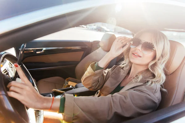 Foto de rubia en gafas de sol mientras conduce en coche — Foto de Stock