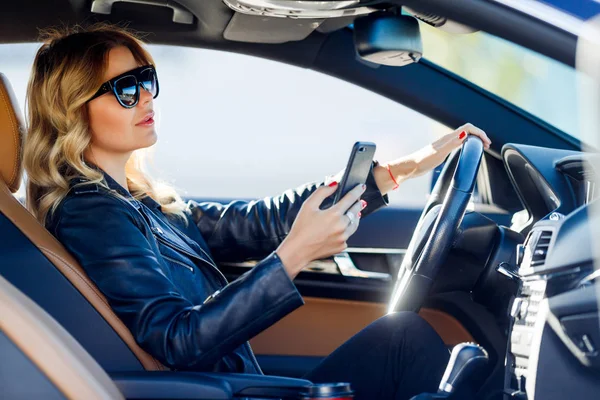 Фото молодой женщины в черных очках с сотовым телефоном в машине — стоковое фото