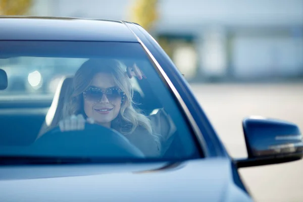 Фотография красивой блондинки в солнечных очках, сидящей в черном автомобиле в течение дня . — стоковое фото