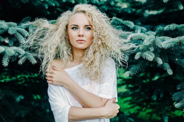 Foto de una mujer rizada de pelo largo junto a las ramas de abeto — Foto de Stock