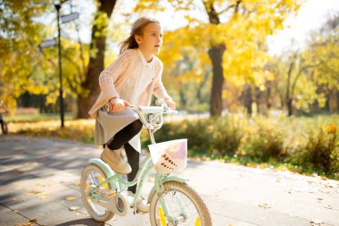 Kız etek sonbahar parkta Bisiklete binmek görüntüsünü