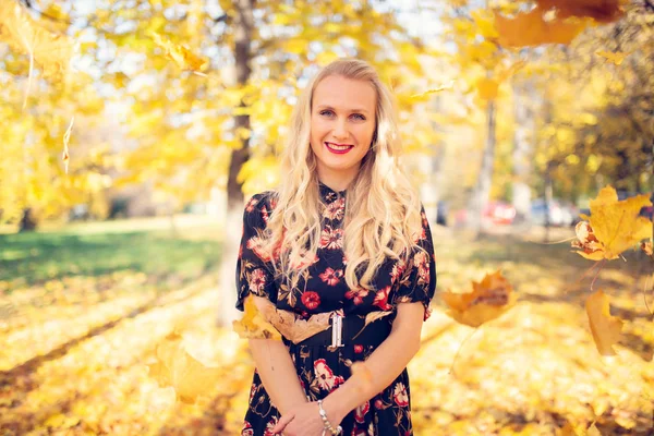 Imagen de la mujer sonriente en vestido sobre fondo borroso del parque de otoño — Foto de Stock