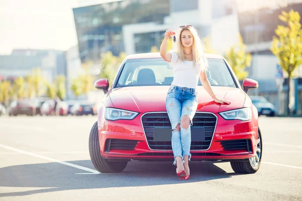 Snímek šťastné blond ženy s klíči stojící vedle červené auto — Stock fotografie