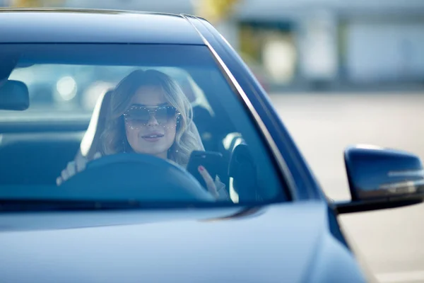 Изображение красивой блондинки в солнечных очках, сидящей в черной машине в течение дня . — стоковое фото