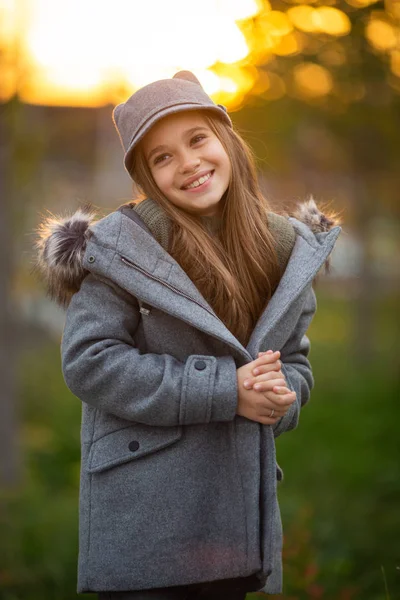 灰色の帽子や都市で背景をぼかした写真のコートの女の子の写真 — ストック写真
