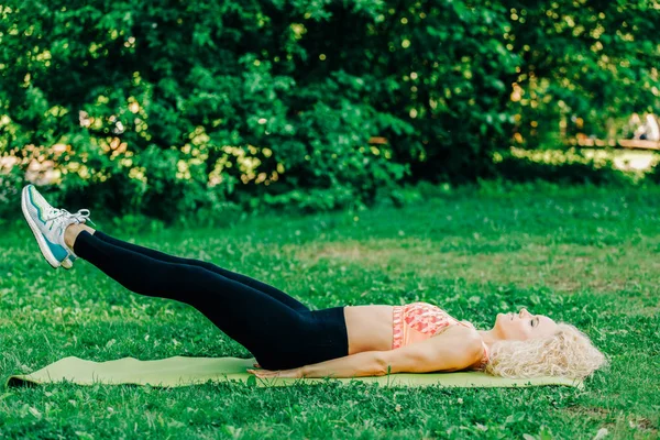 Beeld van jonge curly-haired sport vrouw beoefenen van yoga op tapijt — Stockfoto