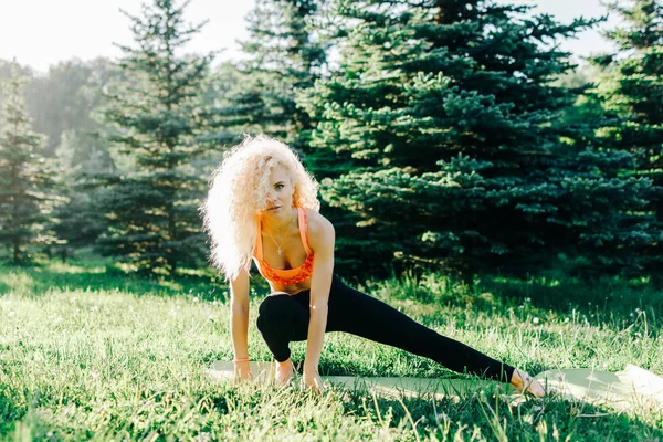 Foto della giovane donna sportiva dai capelli ricci che pratica yoga sul tappeto — Foto Stock