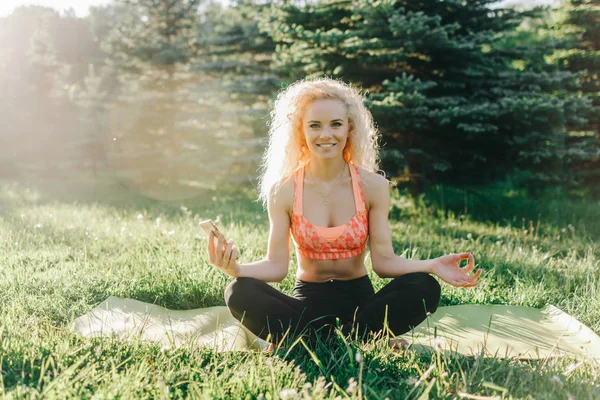 Bilden av ung curly-haired sport kvinna utövar yoga på matta — Stockfoto