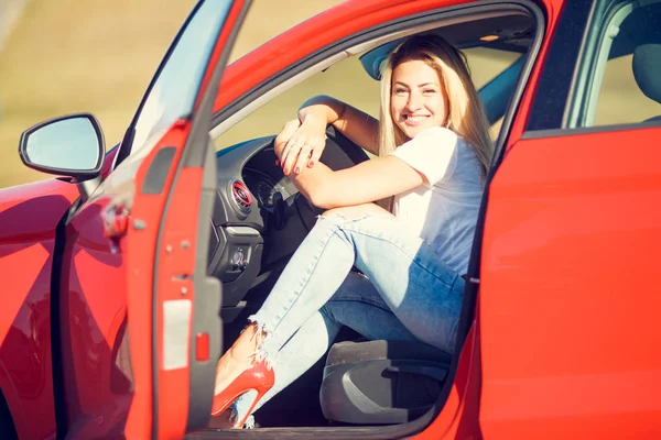 Foto Mladá blondýnka sedí červené auto — Stock fotografie