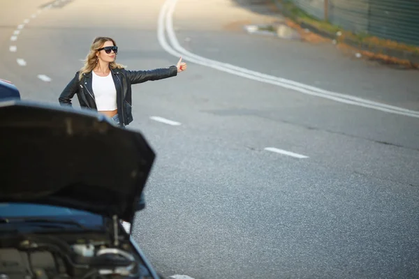 Imagem da jovem mulher com a mão levantada de pé perto do carro quebrado com capuz aberto em — Fotografia de Stock